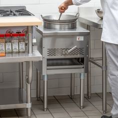 a man standing in front of a pot on top of a stove next to a counter