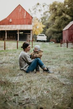 a woman sitting on the ground holding a baby