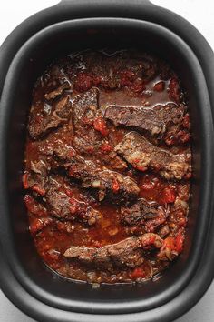 a slow cooker filled with beef and tomato sauce, ready to be cooked in the crock pot