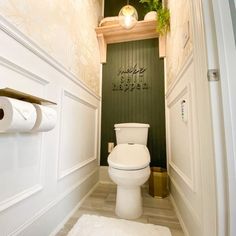 there is a toilet in the bathroom with green walls and wood trimmings on the wall