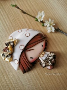 a ceramic figurine is sitting on a table next to some flowers and a branch