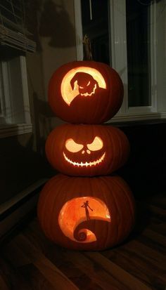 three pumpkins with faces carved into them sitting on the floor in front of a window