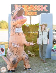 a woman standing next to an inflatable dinosaur