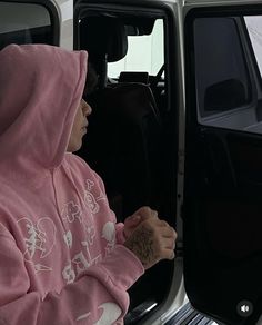 a woman in a pink hoodie sitting next to a white van