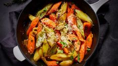 a skillet filled with carrots and other vegetables on top of a black cloth