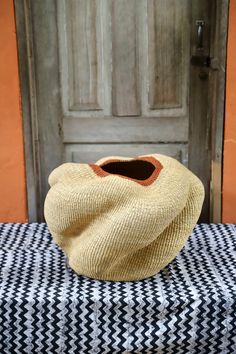 a brown vase sitting on top of a black and white checkered cloth covered bench