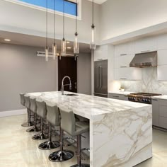 a kitchen with marble counter tops and stools in front of an island that's surrounded by stainless steel appliances