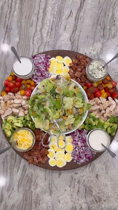 a platter filled with salads and dressings on top of a marble table