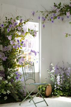 a chair sitting next to a window covered in purple flowers