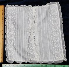 a piece of white lace sitting on top of a table next to a measuring ruler