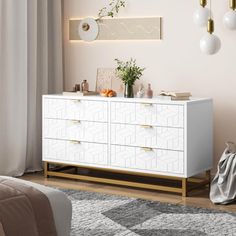 a white dresser with gold handles and drawers in a pink room next to a window