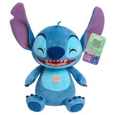 stitcher plush toy with purple ears and blue body sitting next to tag on white background