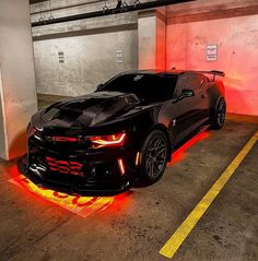 a black chevrolet camaro is parked in a parking garage with red flames on the floor