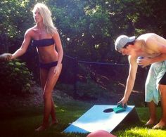 two people in bikinis are playing cornhole game