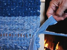 a hand is pulling the edge of a piece of blue knitted fabric from a fireplace