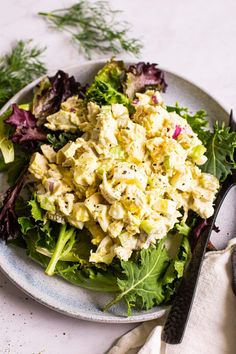 a plate with salad on it next to some utensils and a spoon in the background