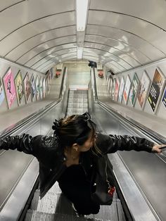 a woman riding an escalator with her arms outstretched in front of the camera