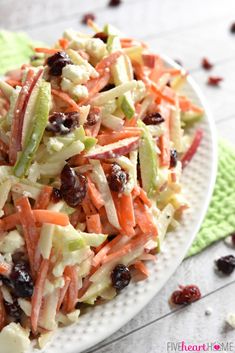 a salad with carrots, celery and raisins on a white plate