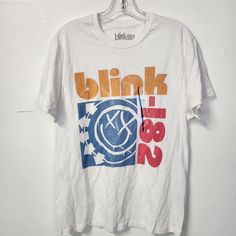 a white t - shirt with the words blink on it hanging from a hanger