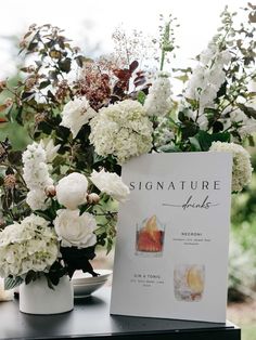 there are flowers in vases on the table with a sign that says signature drinks