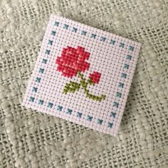 a cross stitch rose on a white cloth