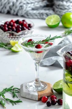 cranberry and rosemary martini in a coupe glass with limes on the side