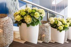 three white vases with flowers in them sitting on a ledge next to some stairs