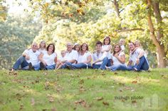 a group of people sitting on top of a lush green field next to each other