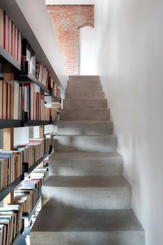 there are many books on the shelves next to the stairs that lead up to the second floor