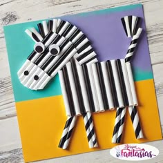 a zebra made out of construction paper on top of a piece of cardboard with black and white stripes