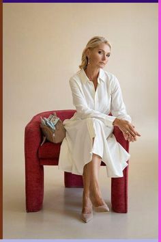 a woman sitting on top of a red couch next to a pink frame with an image of her legs crossed