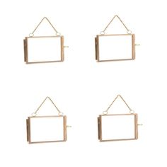 four metal frames hanging from chains on a white wall, each with a square and rectangle shape