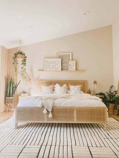 a large bed sitting in the middle of a bedroom next to a window with potted plants