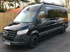 a black van parked in front of a wooden fence