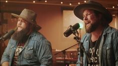 two men in cowboy hats singing into microphones