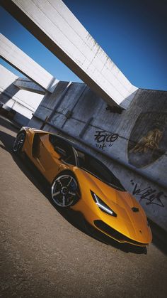 a yellow sports car parked in front of a concrete structure with graffiti on the walls