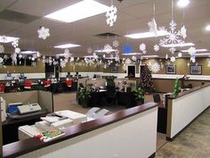 an office decorated for christmas with snowflakes hanging from the ceiling and desks