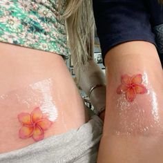 two women with tattoos on their stomachs and one has a flower painted on it