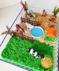 a plastic container filled with fake farm animals and grass on top of a white table