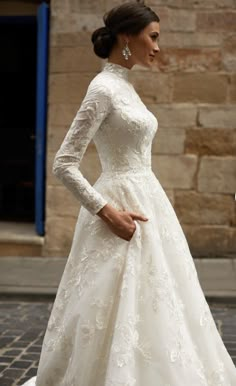 a woman in a white wedding dress is standing on the street with her hand on her hip