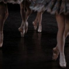 the feet of three ballerinas in tutu skirts