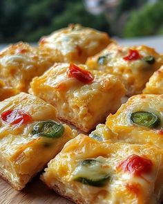 several pieces of pizza sitting on top of a wooden cutting board with cheese and peppers