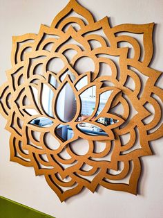 a mirror that is on the wall in front of a flower shaped frame with an intricate design