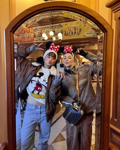 two people dressed up as mickey and minnie mouse in front of a mirror with the reflection of them