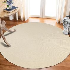 a round rug on the floor with a chair and table in the corner behind it