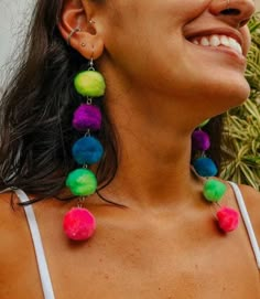 a woman smiling and wearing colorful earrings