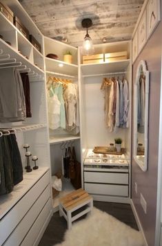 a walk in closet with white shelving and shelves filled with clothes on hangers