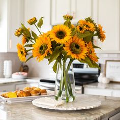 a vase filled with yellow sunflowers sitting on top of a counter next to pastries