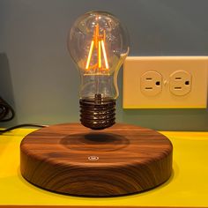 an electric light bulb sitting on top of a wooden table next to a power outlet