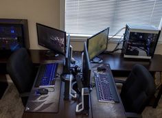 there are three computers on the desk with their keyboards and mouses in front of them